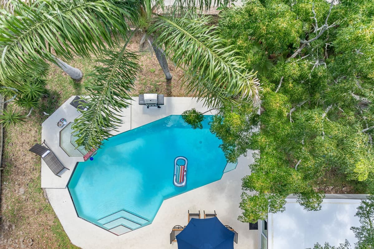 The pool is a centerpiece of tranquility, surrounded by lush landscaping that enhances its serene ambiance.