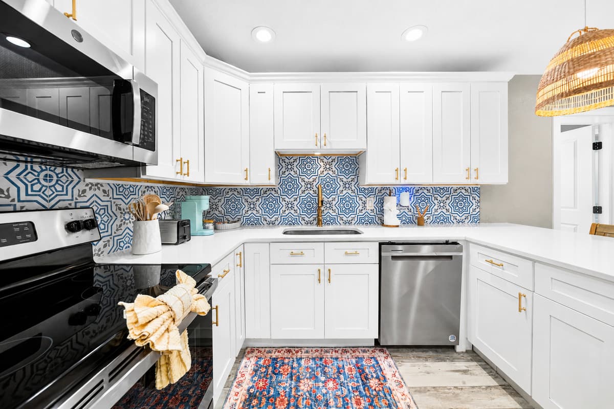 Functional chef's kitchen with generous counter space, modern finishes, and a colorful decorative backsplash.
