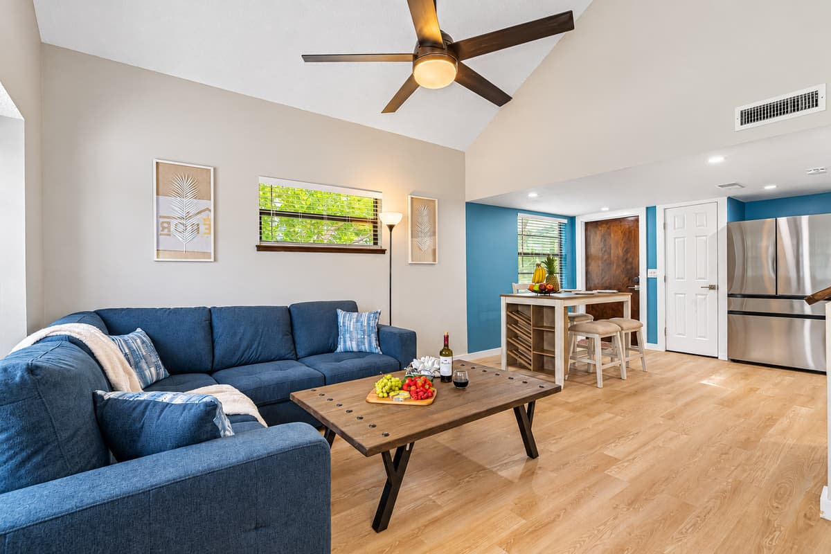 Step into a world of refined sophistication where a soothing color palette, a plush blue sofa, expansive windows, and warm wooden floors come together to create an inviting haven.