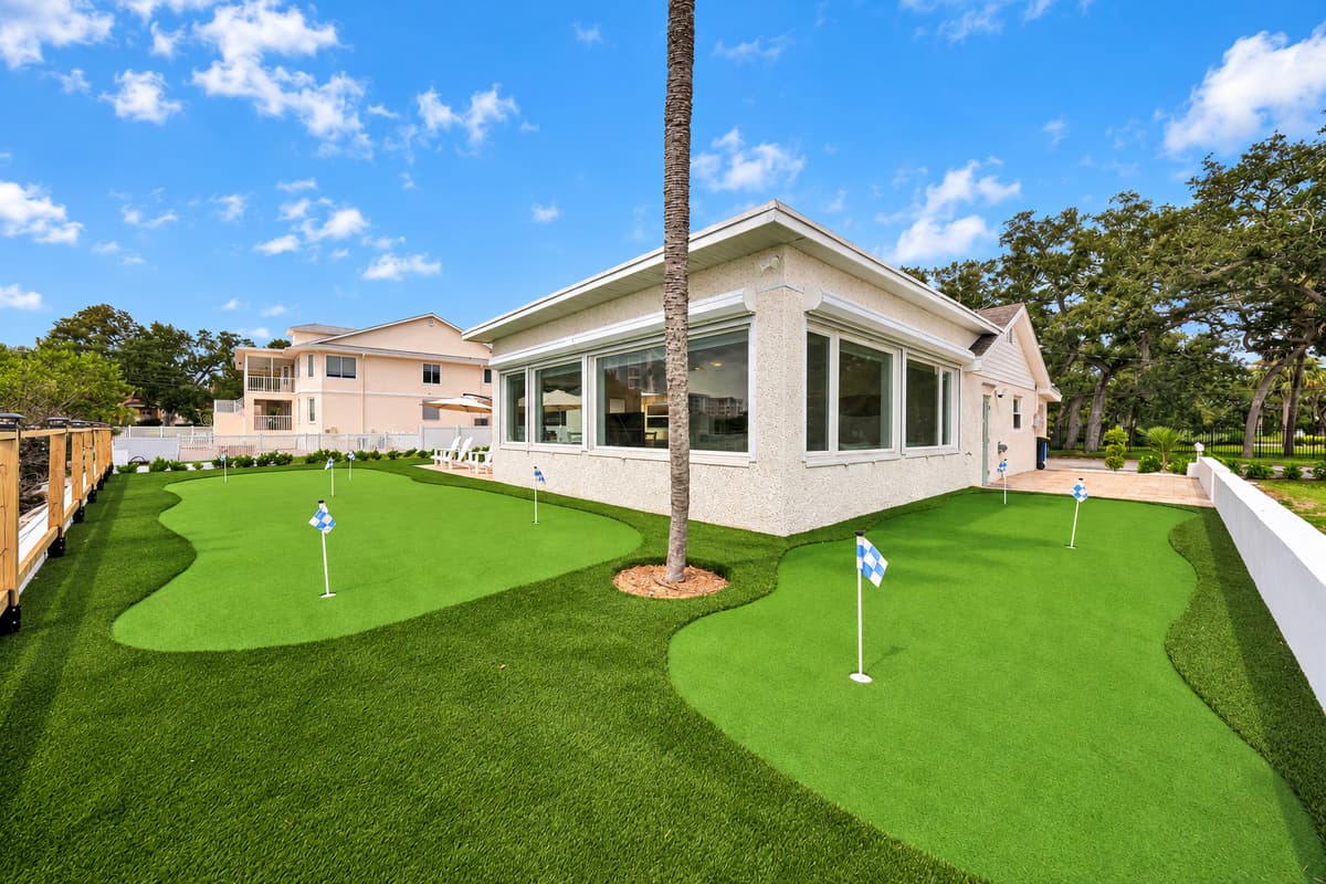 Your own private putting green. Practice your short game steps from the back door. Multiple holes, flags and soft turf beside the house, with the bay just past the fence.