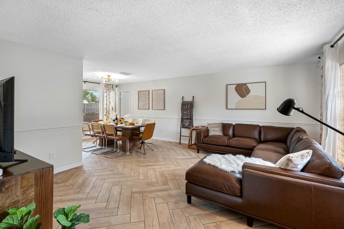 This open-concept living room boasts a leather sectional, designer lighting, and soft touches like fur throws and woven textures—perfect for catching up, streaming a show, or simply relaxing.