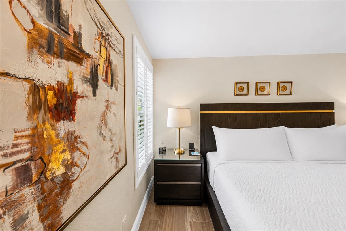 Comfortable king bedroom with stylish artwork, cozy lighting, and relaxing neutral tones.