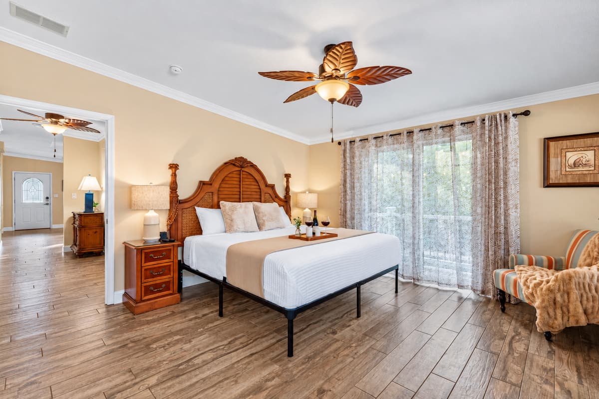 This serene master suite offers a spacious retreat with elegant coastal décor and warm natural light flowing through the large windows.