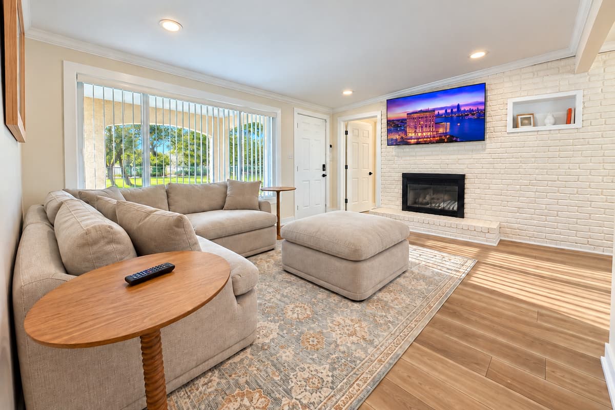 Front living room with sectional seating, TV and fireplace feature.