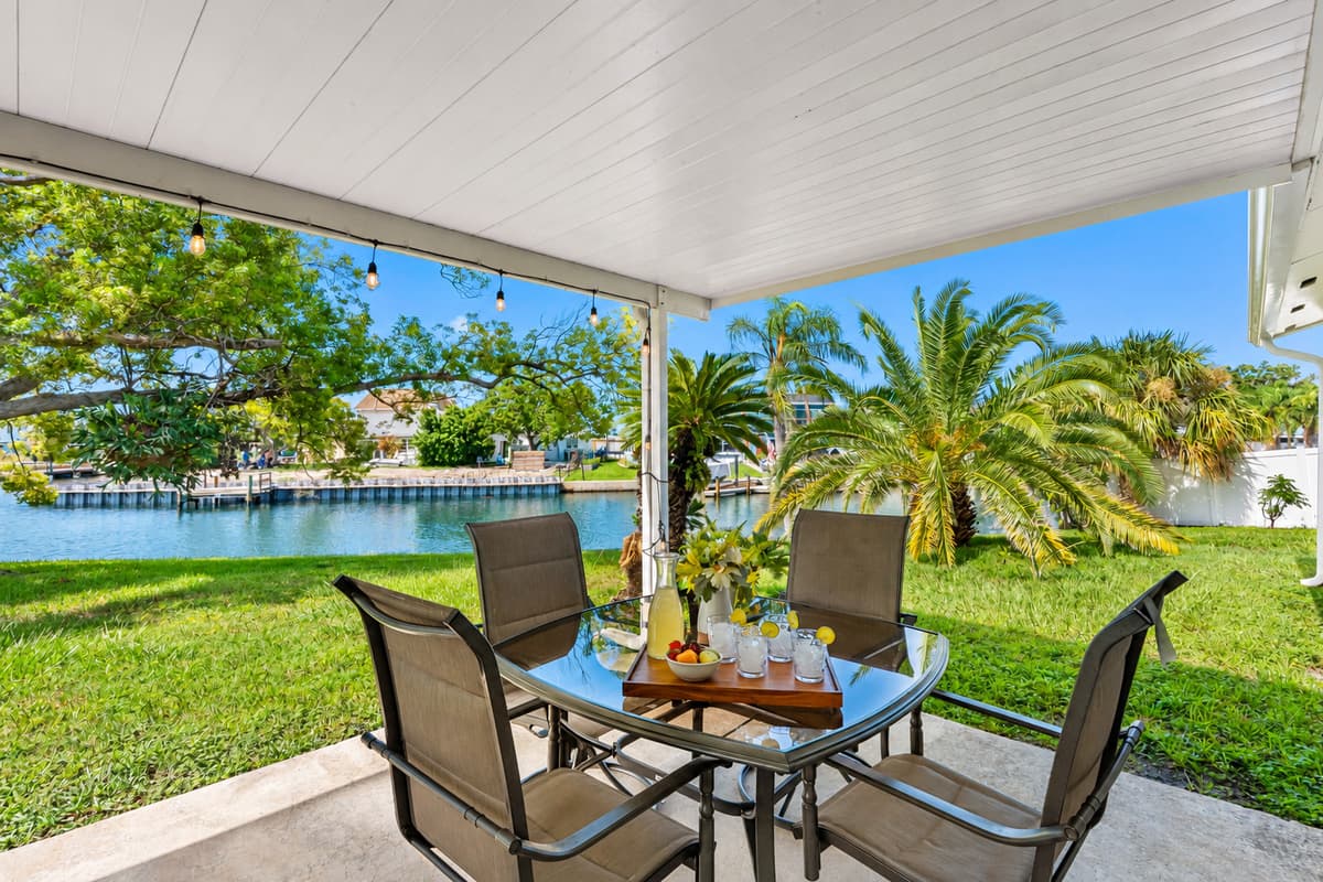 Enjoy tranquil mornings and breezy afternoons on this covered patio that overlooks a peaceful canal and lush palm trees.