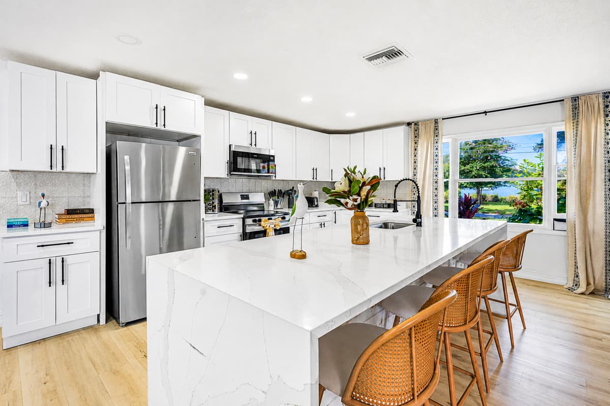 Window over the sink, island in the middle, stools facing in — somebody is always keeping you company.
