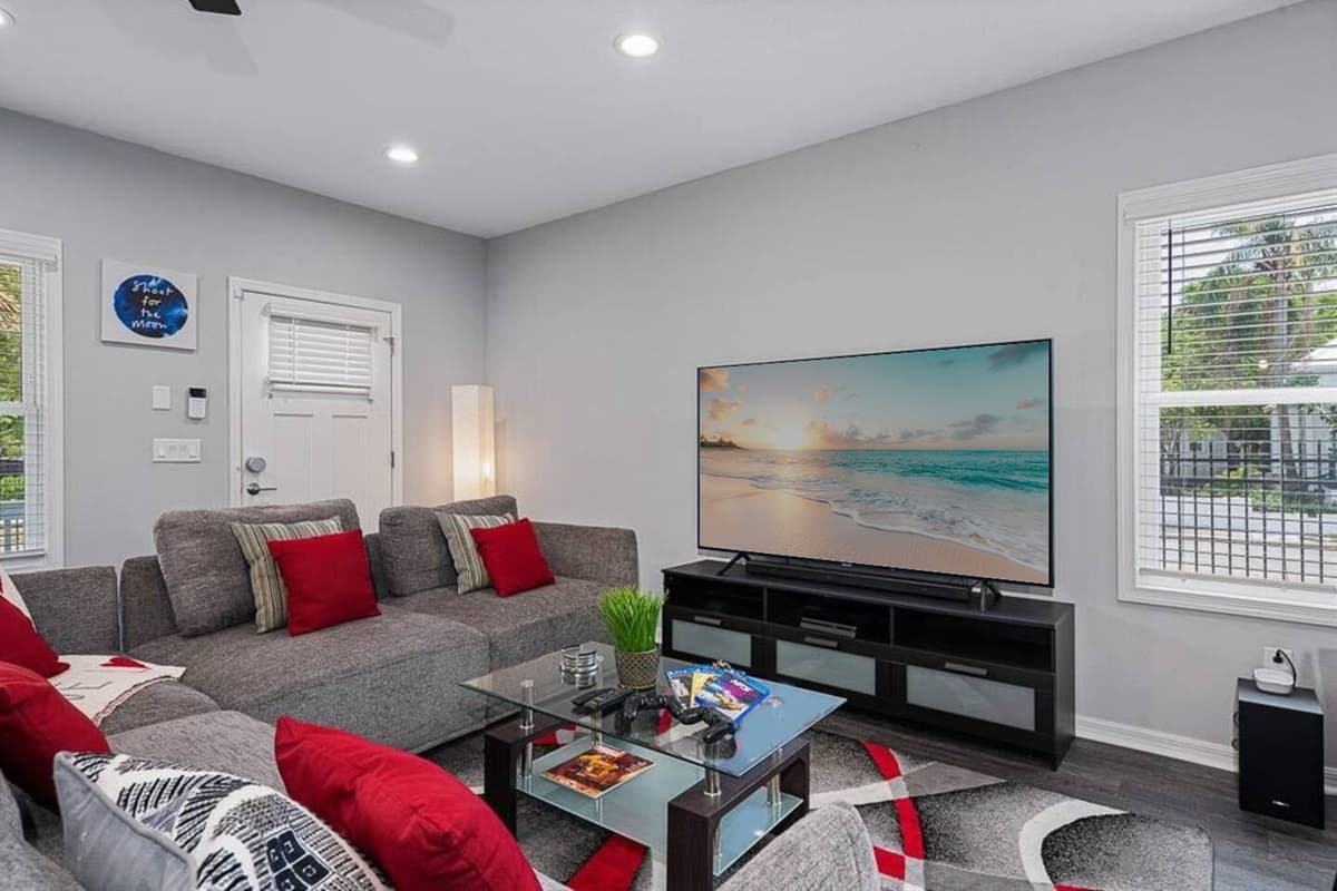 The grey pillows add a touch of sophistication and balance, while the pops of red inject a vibrant energy into the space, creating a visually captivating contrast.