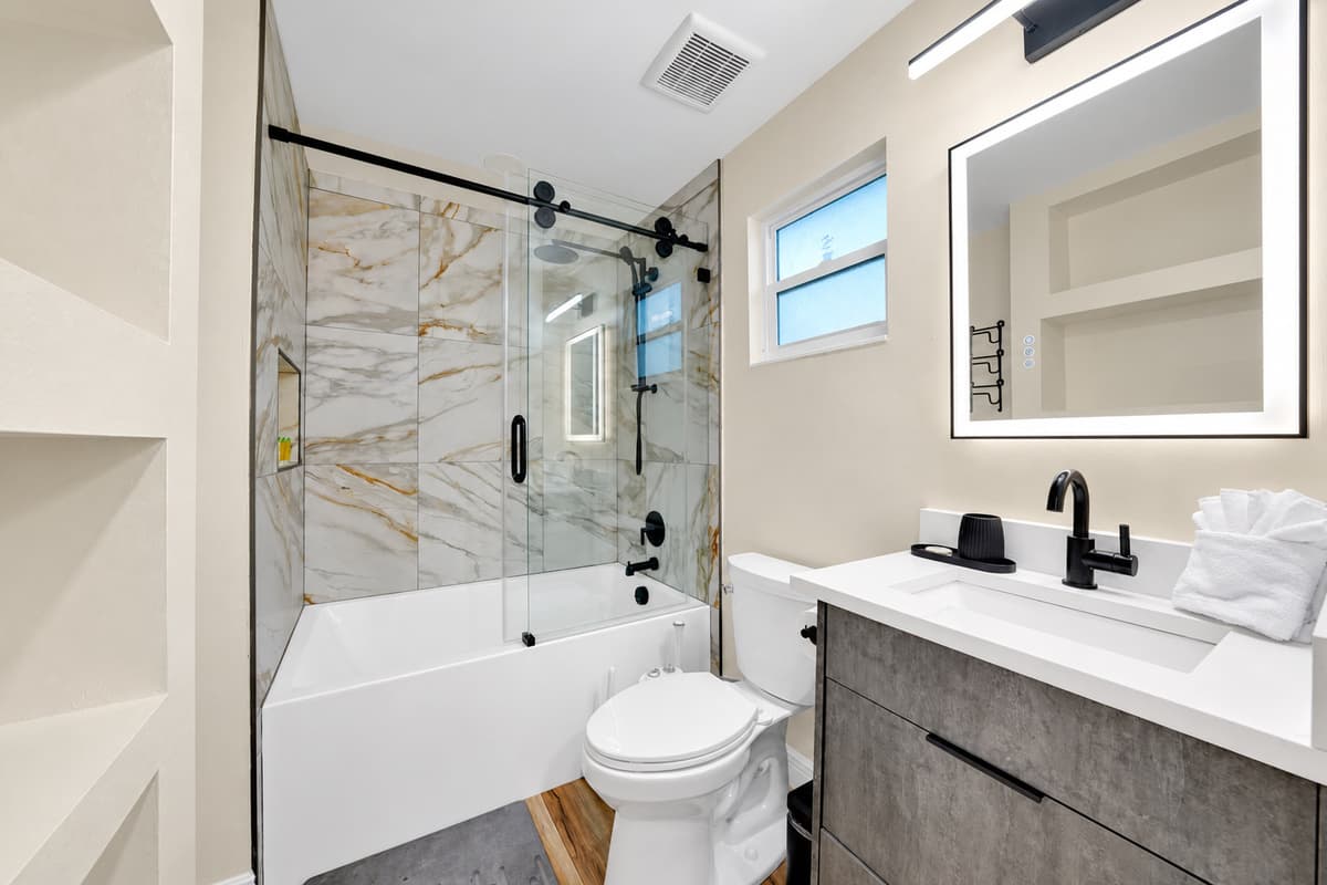 A tub, for the one night you don't want the pool. Full bath and shower behind glass, lit mirror and a proper vanity — private, warm and steps from the bed you're sleeping in.