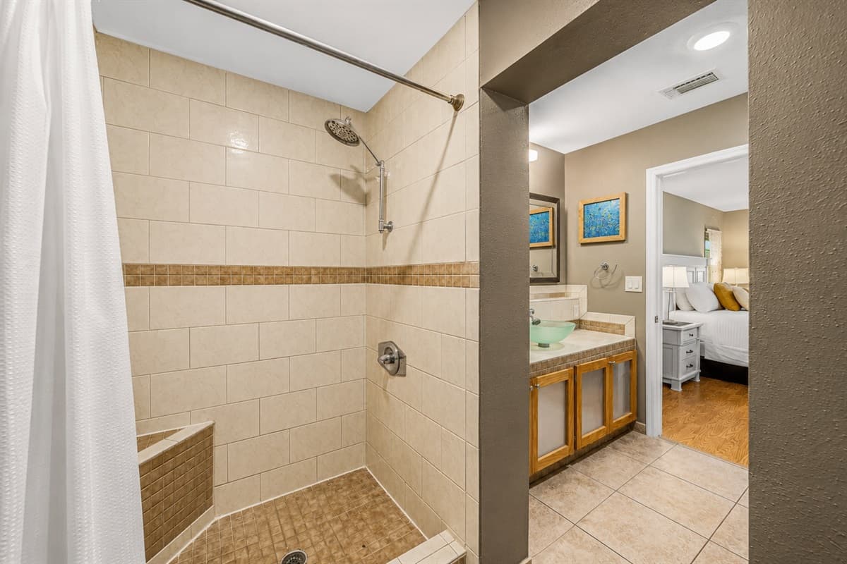 Spacious primary bathroom featuring a large walk-in tiled shower and direct access to the bedroom.