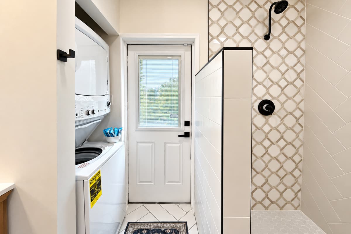 Walk-in shower and stacked laundry area in Bathroom 1.