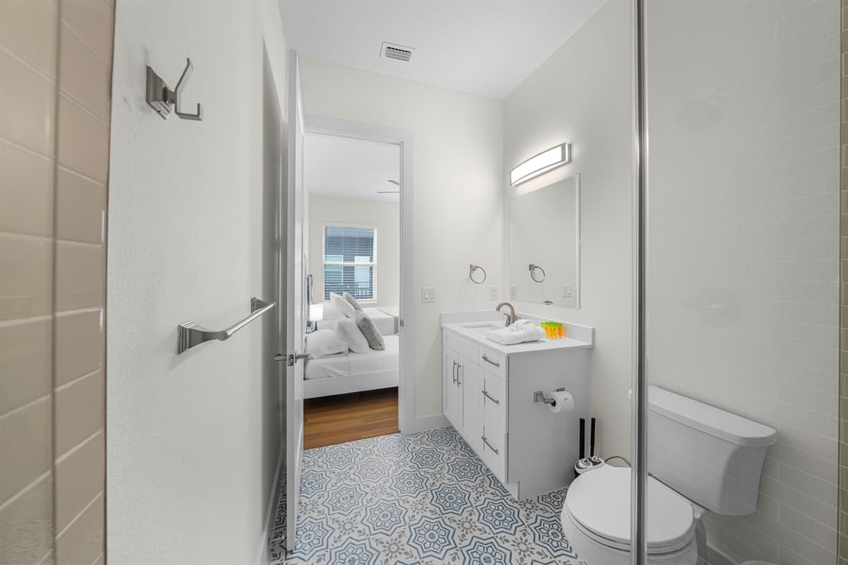 Clean and modern bathroom with stylish tile flooring, bright vanity, and convenient access to the bedroom.