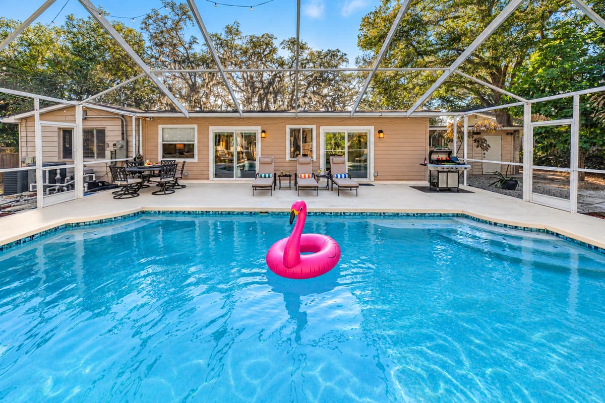A spacious screened-in pool area featuring a sparkling private pool, and patio seating —perfect for soaking up the Florida sunshine.