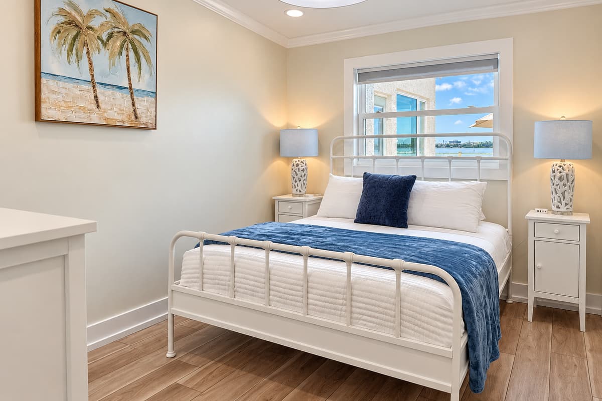 Queen bedroom with a white metal bed frame and smart TV.