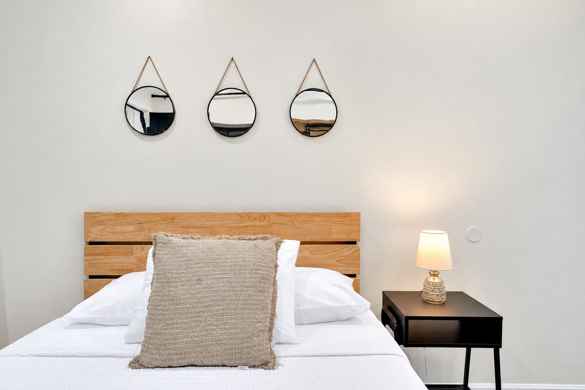 Deep sleep, soft light, no one knocking. Wide bed, warm wood headboard and a bedside lamp for reading, in a quiet corner of the estate where the pool noise never quite reaches.