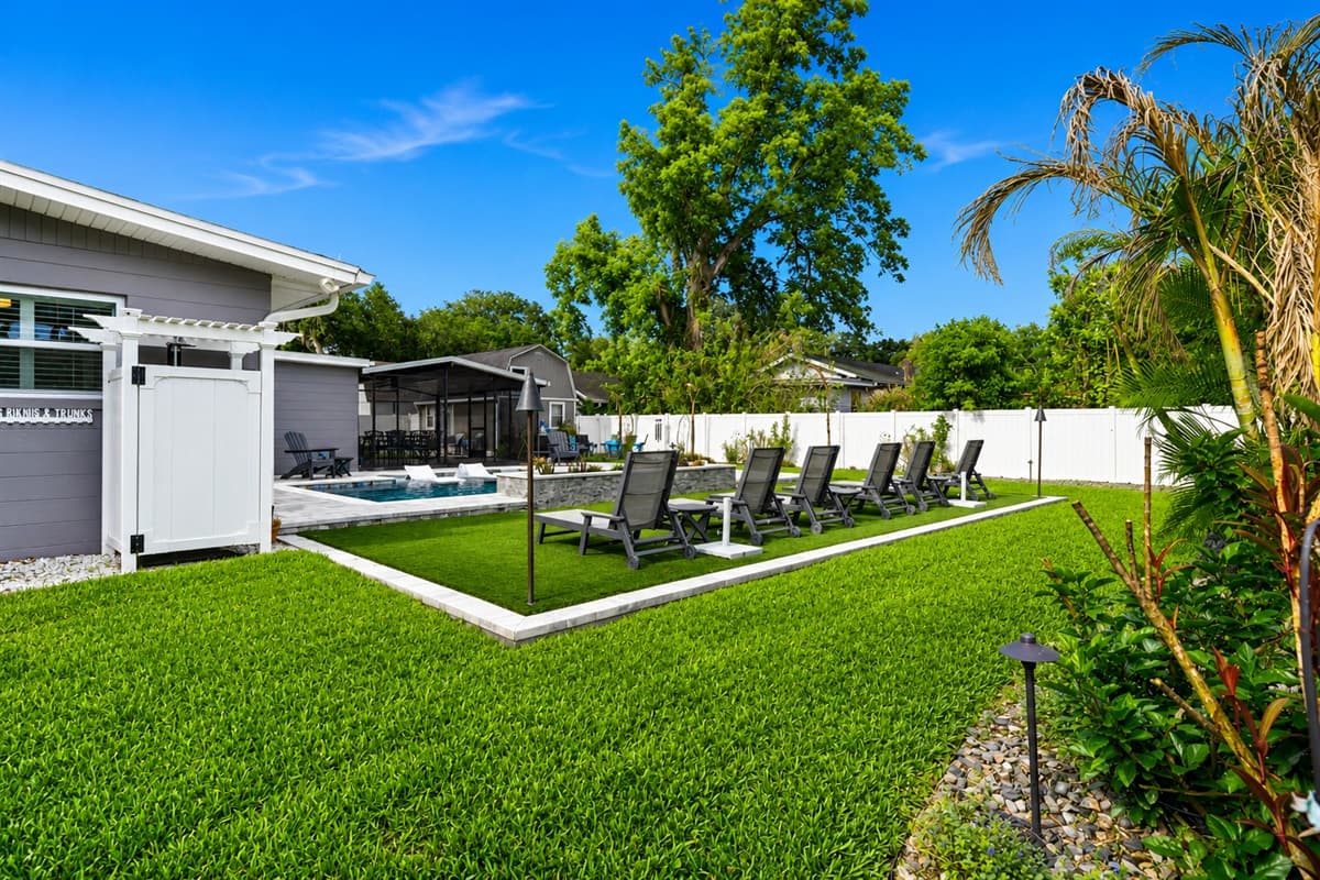 Expansive backyard view featuring the private pool, lounge chairs, screened patio, and open green space.