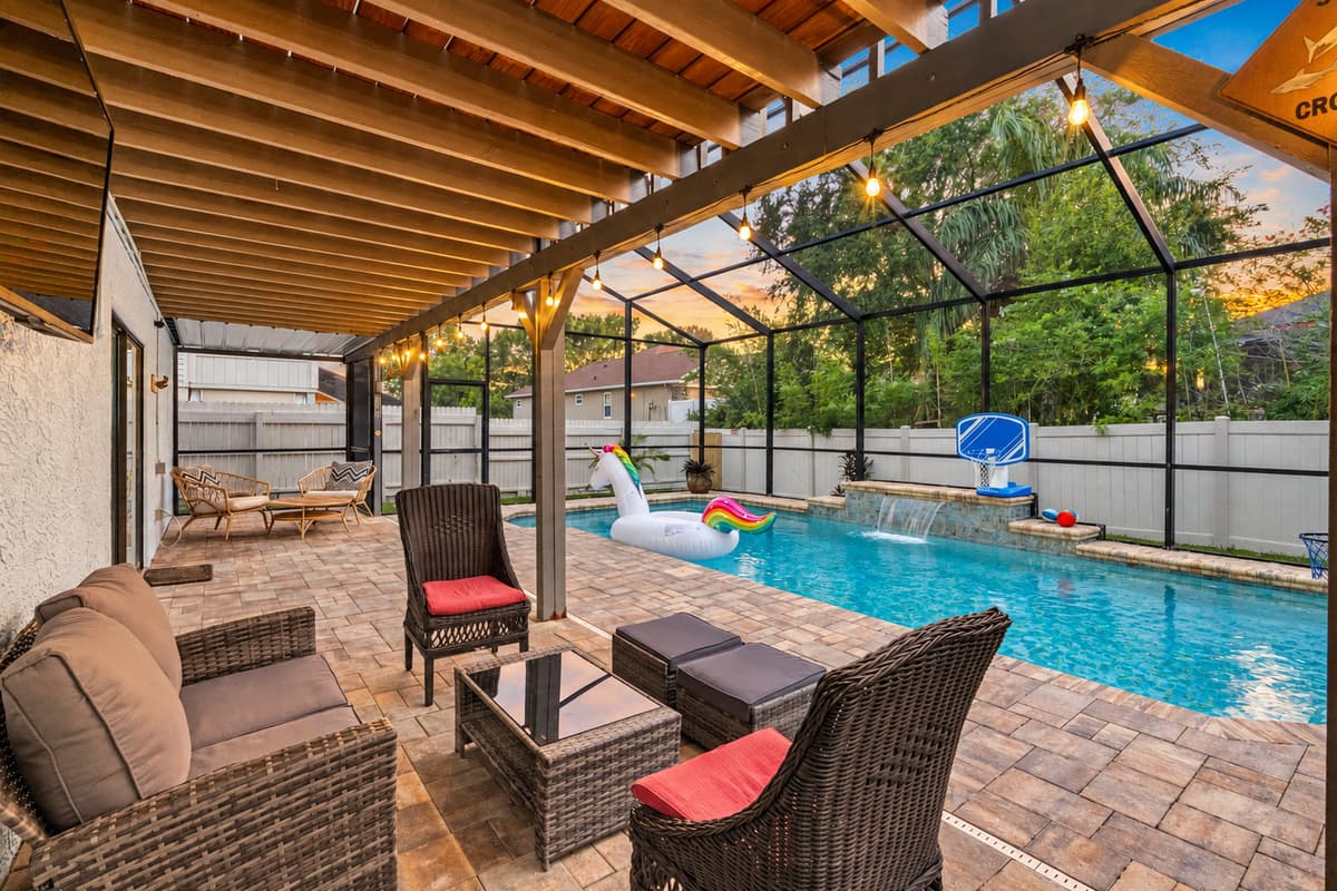 Enjoy resort vibes with this spacious screened-in pool area—complete with wicker lounge seating, a shaded patio, and fun inflatables for the whole family.