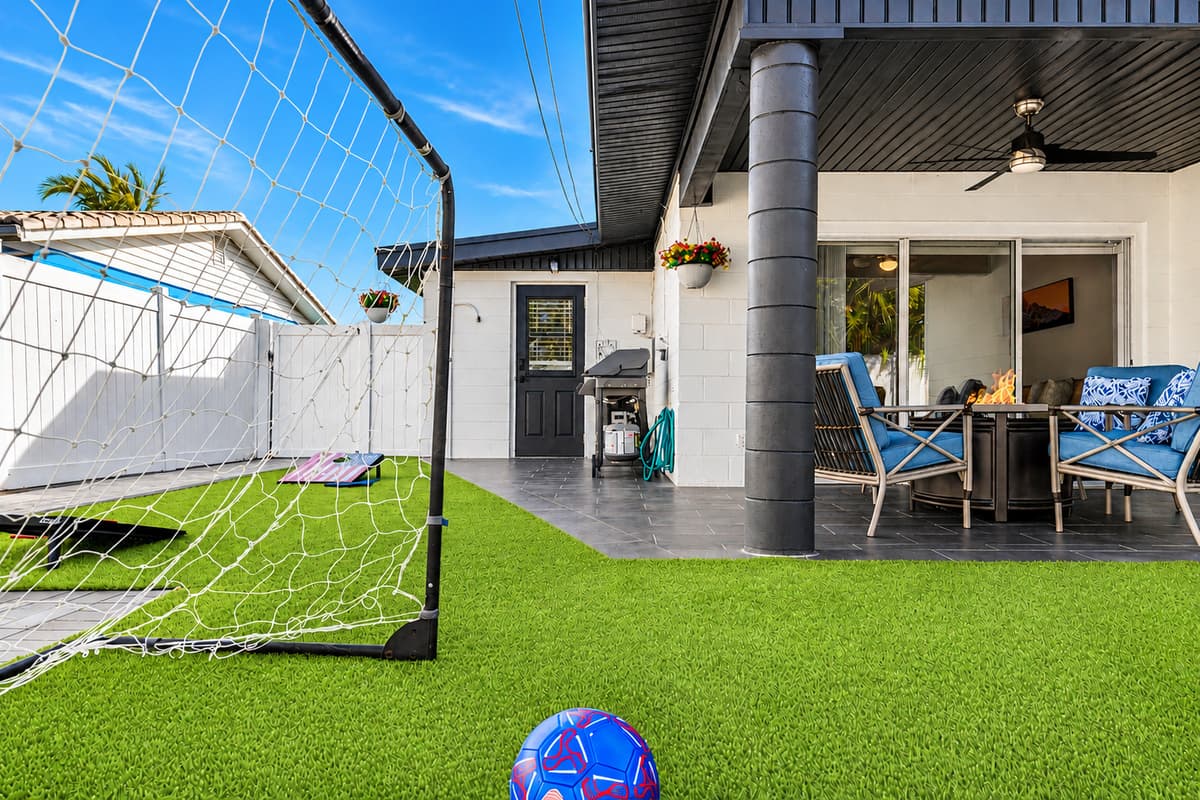 Cozy covered patio with outdoor dining, lounge seating, and backyard play area.