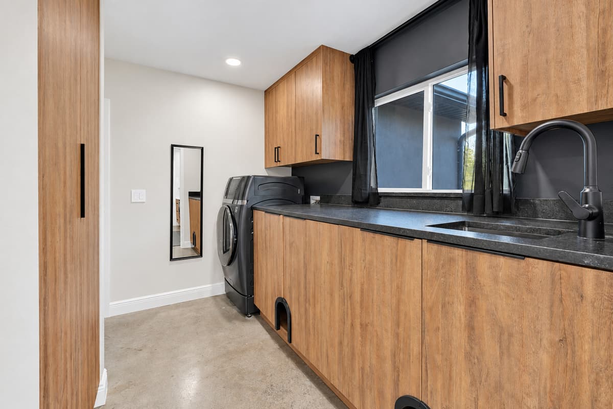 Laundry that doesn't interrupt anyone's afternoon. Full-size machines behind cabinet doors, with counter space above for folding — wet towels handled quietly while the house carries on.