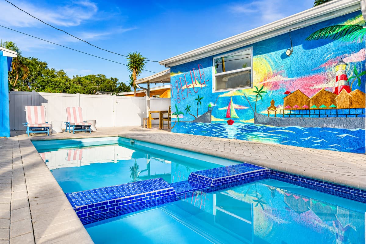 Close-up view of the pool and spa showcasing crystal-clear water, spacious pool deck, and vibrant waterfront-themed mural.