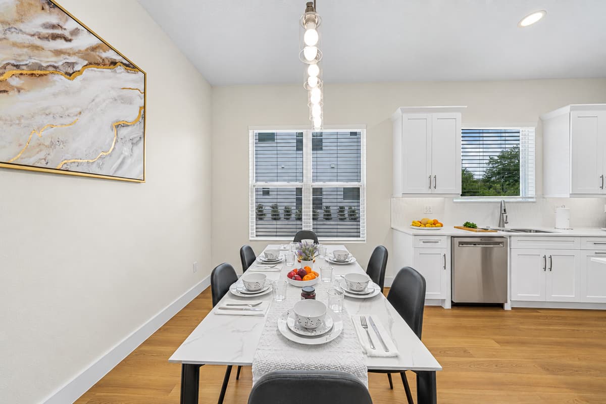 Bright and elegant dining area with seating for guests, set beside a modern kitchen—perfect for shared meals and gatherings.