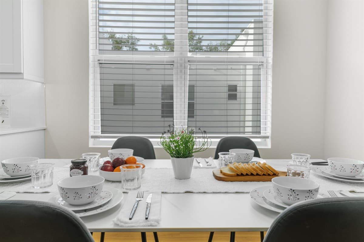 Bright dining table by large windows with natural light and modern table setting.