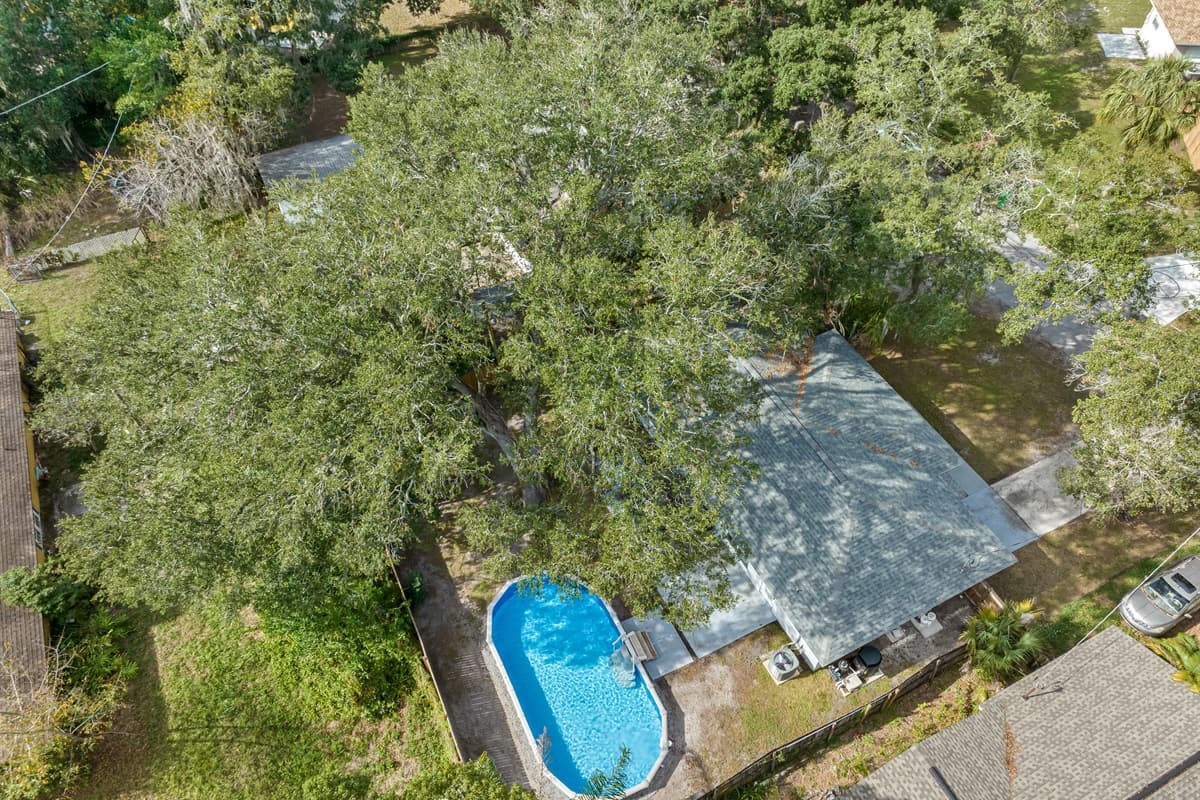Aerial top view of our beautiful house showcasing our incredible heated pool. The property is surrounded by trees and is fully fenced. If you are interested in this property, send us an inquiry now!