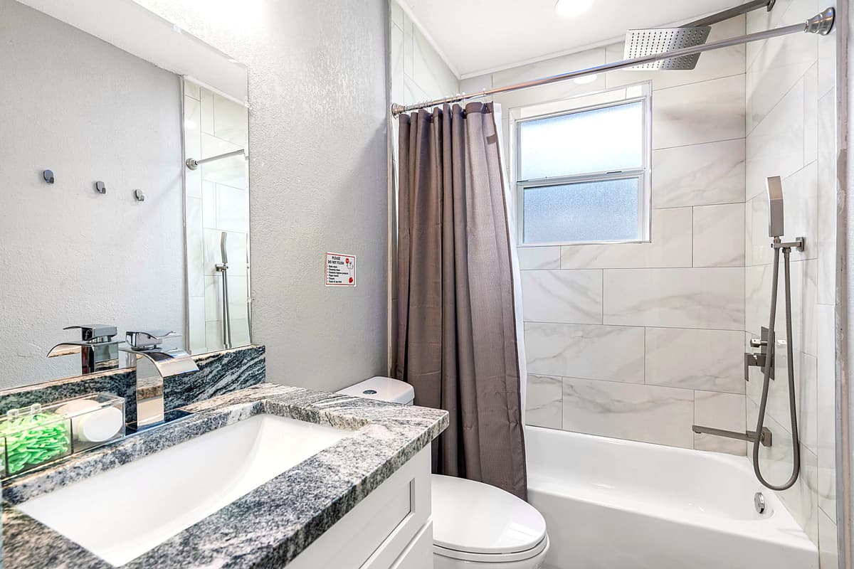 Bathroom with modern tub/shower combo, sleek fixtures, and clean tile finishes.