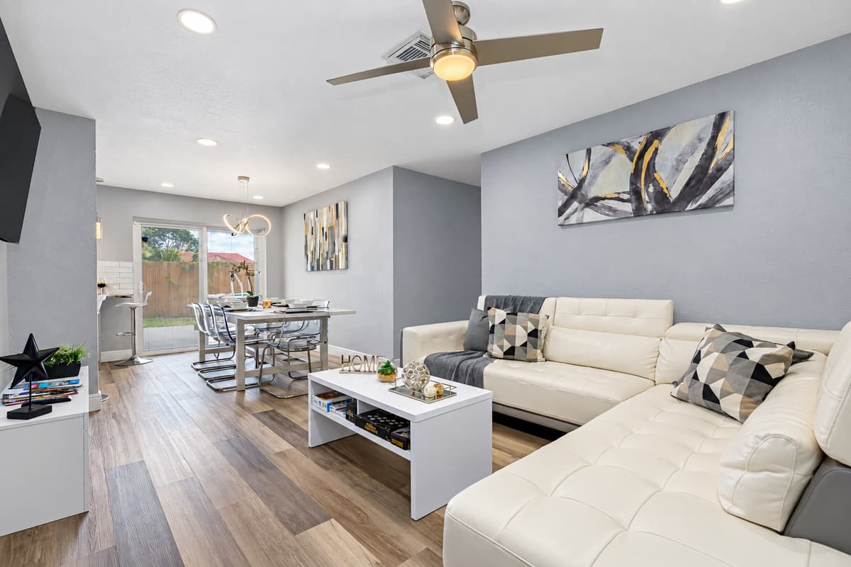 Room for 10 to gather in one open space. An L-shaped sectional, Smart TV, and an 8-seat dining table share one bright, renovated room. Two families can cook, eat, and laugh together without anyone stuck in a corner.