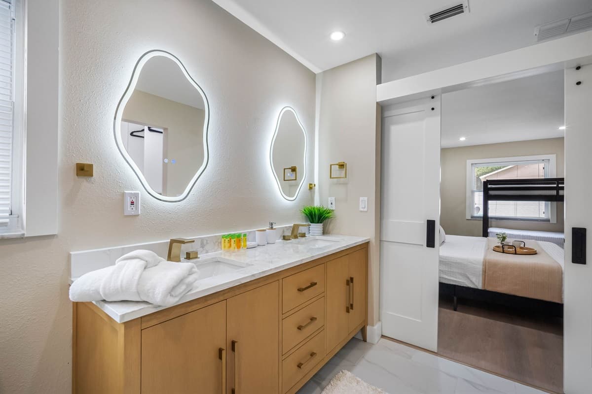 From the glowing backlit mirrors to the rainfall shower and gold accents, this bathroom is designed to impress.