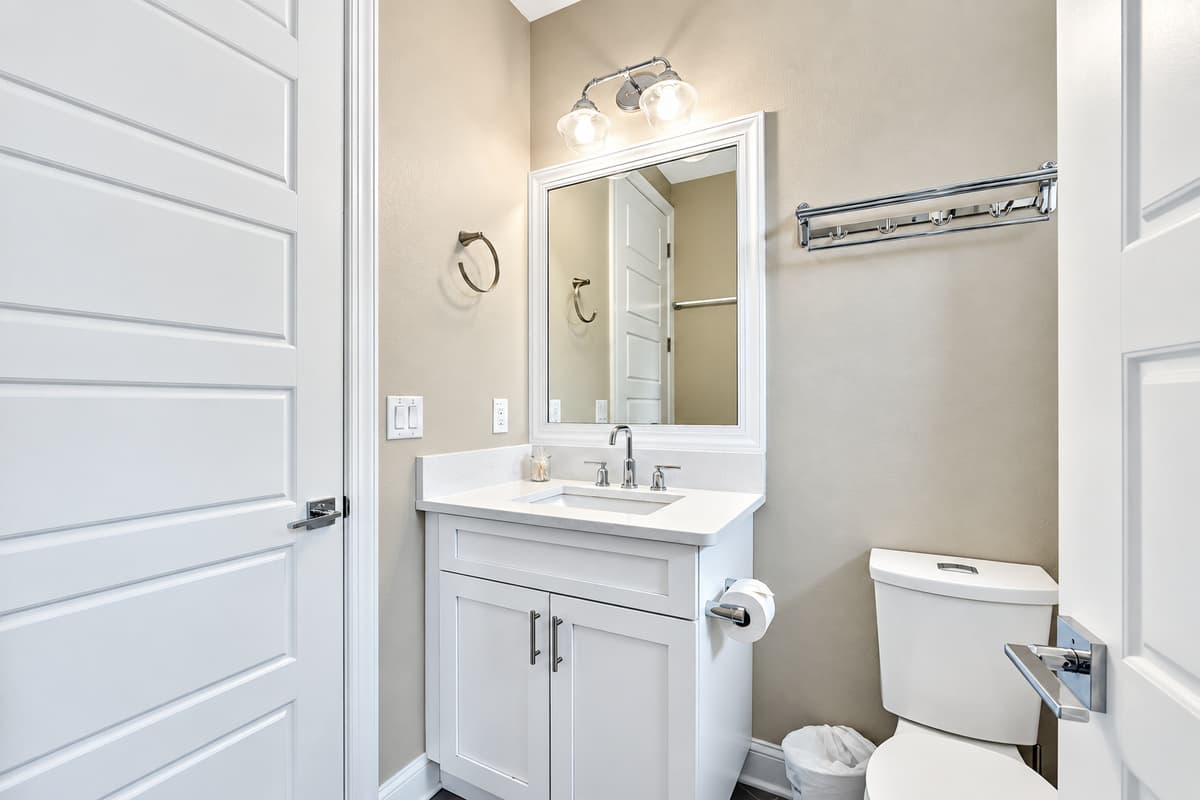 Soft, ambient lighting from overhead fixtures and vanity lights creates a warm and inviting atmosphere, ideal for unwinding after a long day.