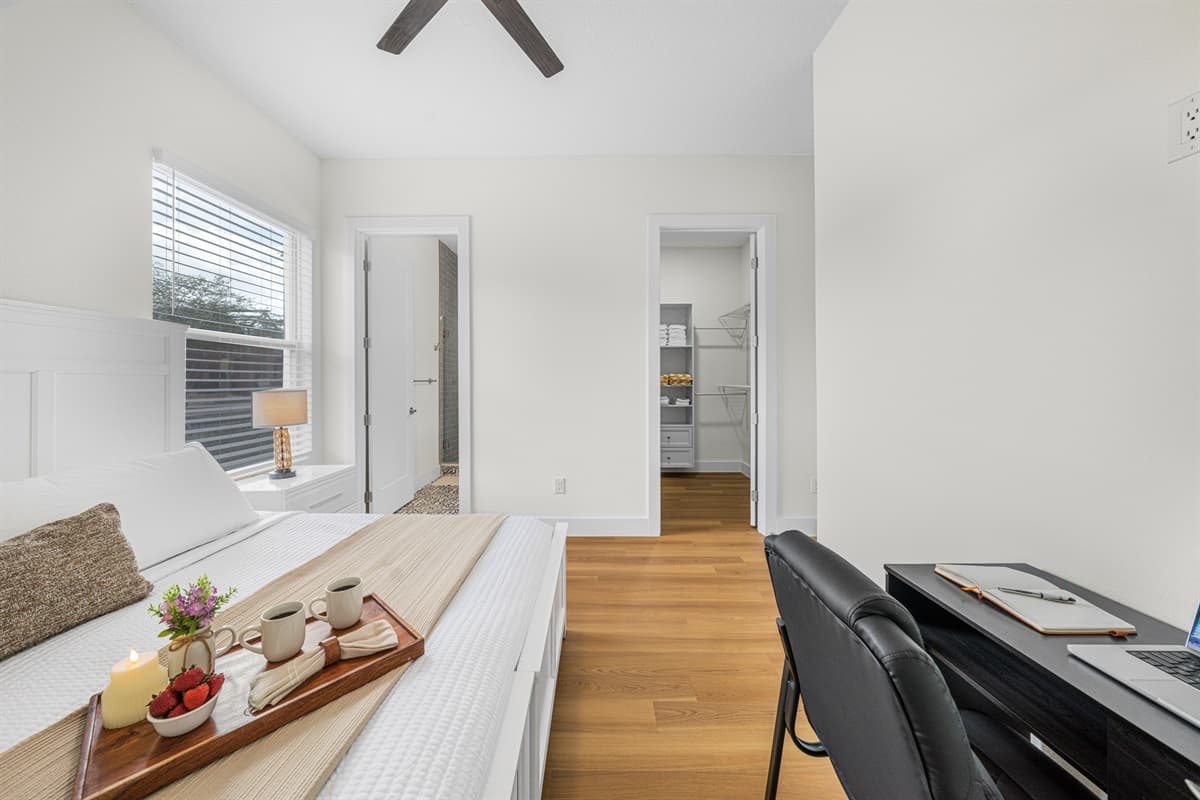 Bedroom with dual workspace setup and easy access to adjacent rooms.
