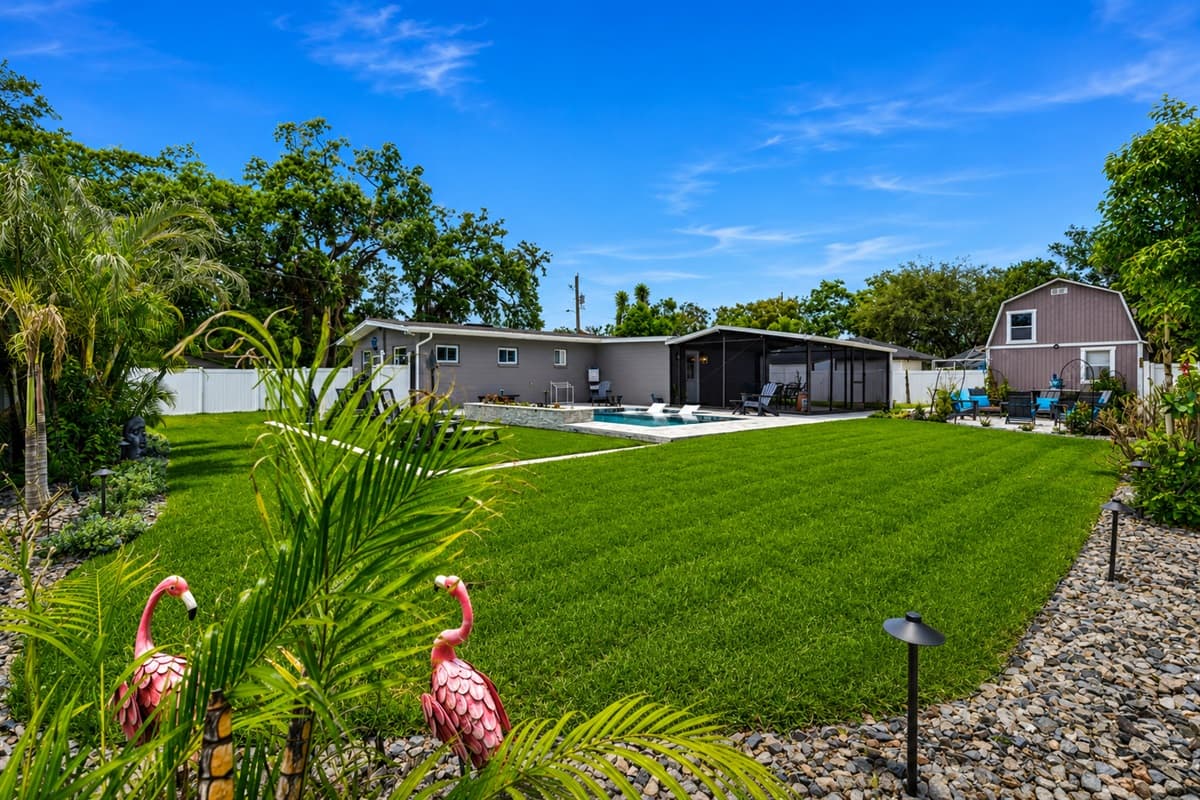Expansive backyard view featuring the private pool, lounge chairs, screened patio, and open green space.