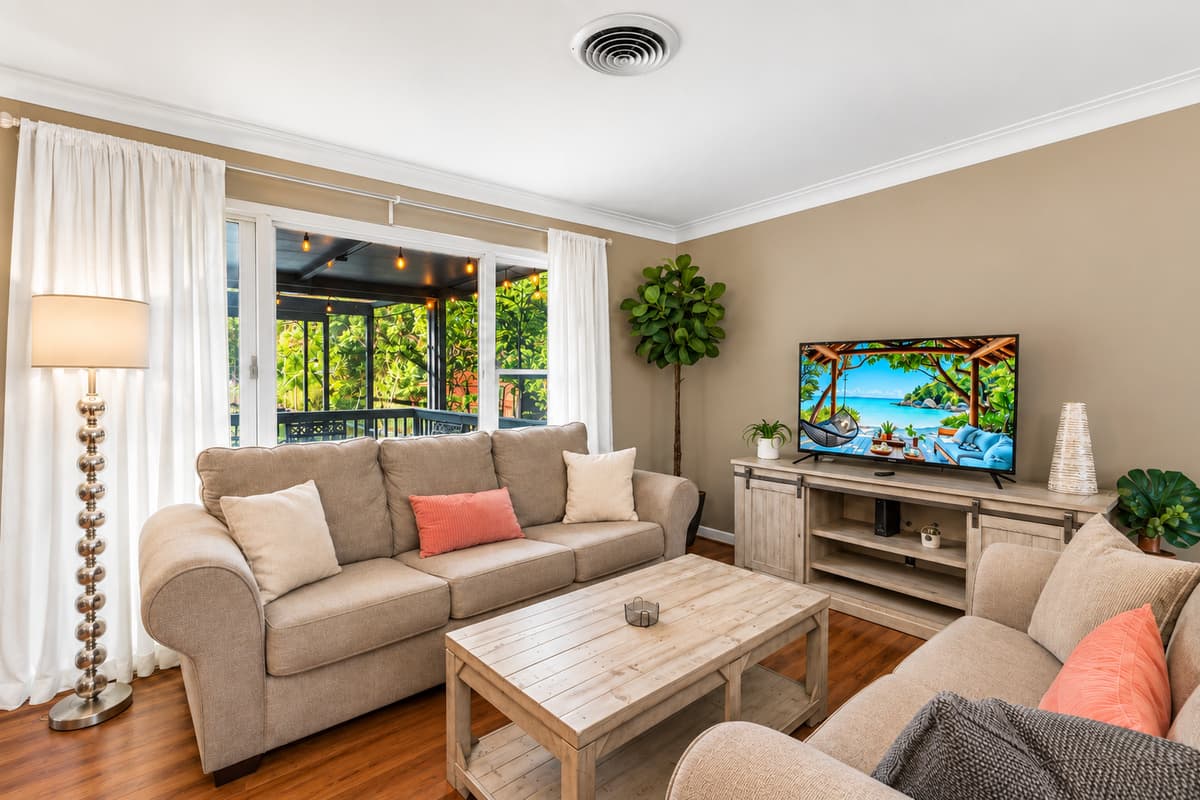 Cozy lounge space with warm lighting, comfortable couches, and backyard views through large windows.