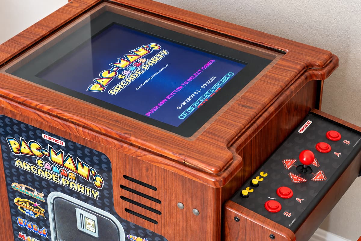 A colorful and casual hangout area featuring comfortable seating, a full laundry setup, and a nostalgic arcade game that adds a playful twist.