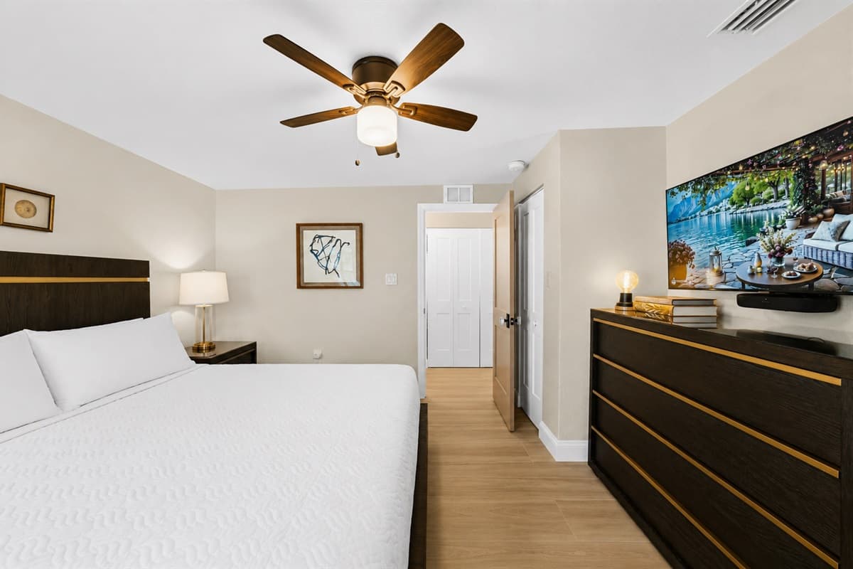 Bright and inviting king bedroom featuring a smart TV, dresser, and spacious layout for added comfort.