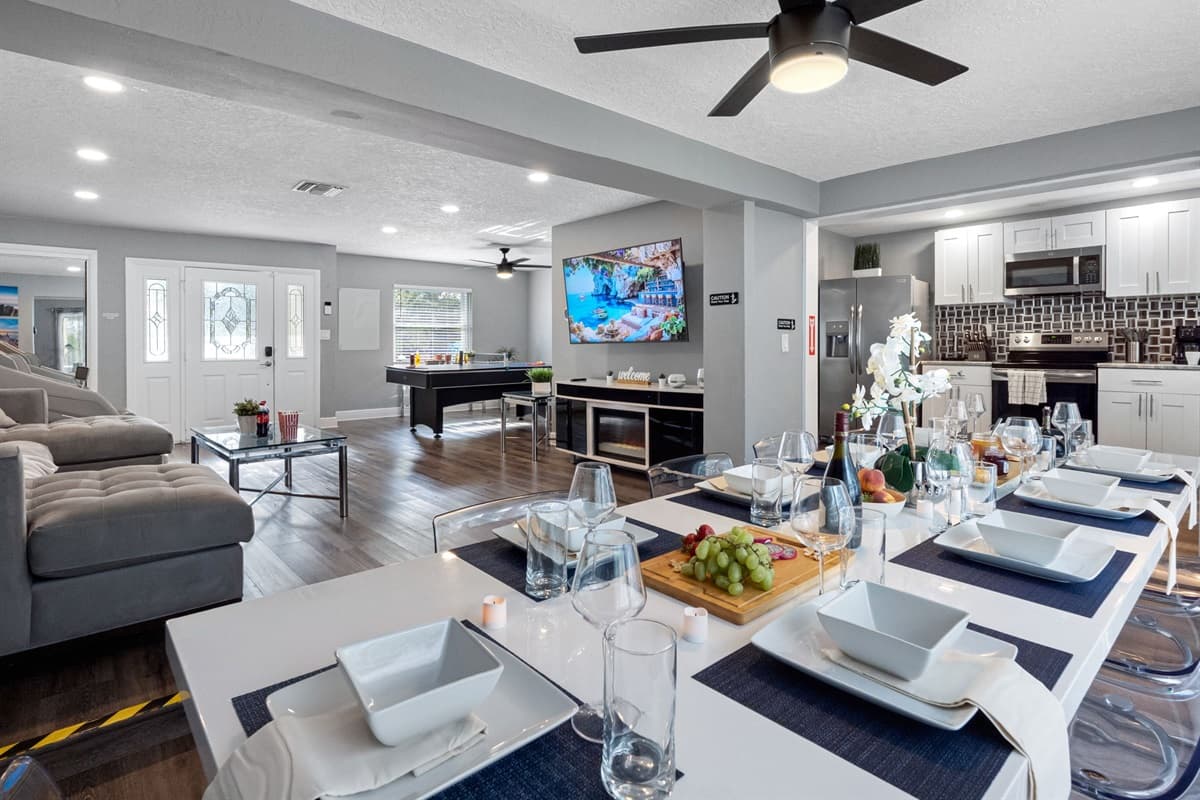 This sleek dining area features a modern white table with transparent chairs, perfect for large groups to gather and enjoy meals in style.
