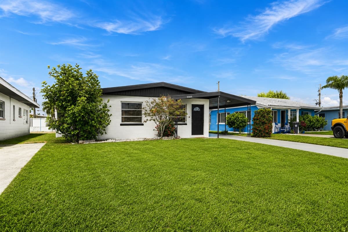 Wide front yard view featuring lush landscaping and modern single-story home design.