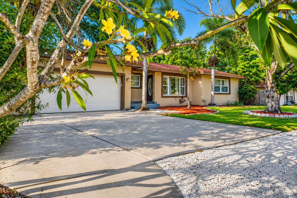 Bright exterior view with ample driveway space and lush Florida landscaping.