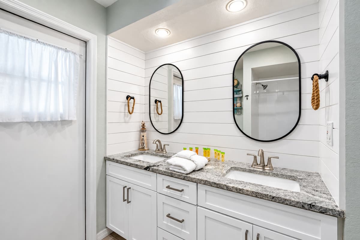 Dual mirrors, bright lighting, and clean finishes create a refreshing space to unwind.