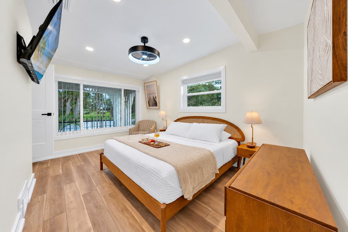 Morning light in the king suite. Wide windows bring in soft light and green views. A king bed, dresser and tray with treats welcome you on arrival.