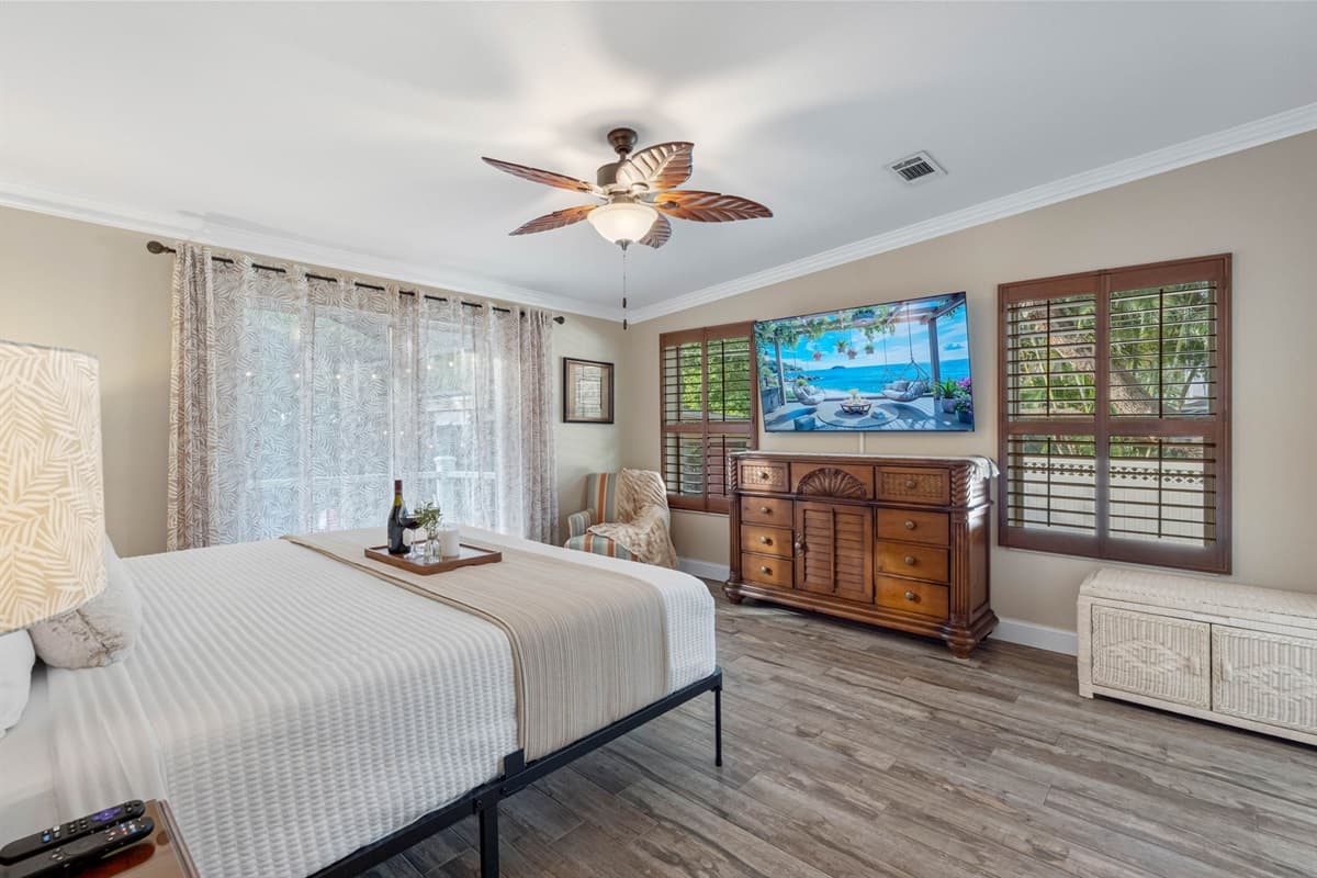 The master suite boasts a resort-like atmosphere with wood accents, large windows, and a peaceful view of the outdoor greenery.