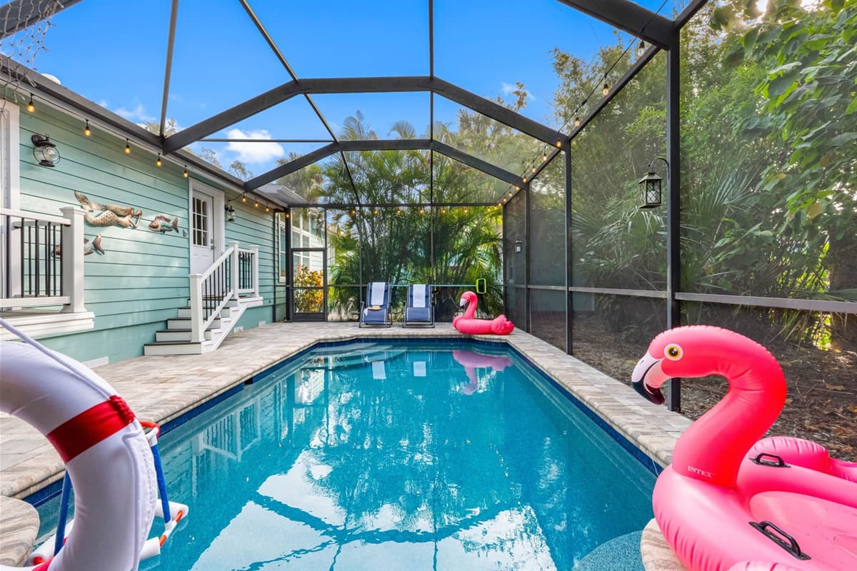 The screened-in pool area blends comfort and fun with loungers, flamingo floats, and a relaxing outdoor living setup.