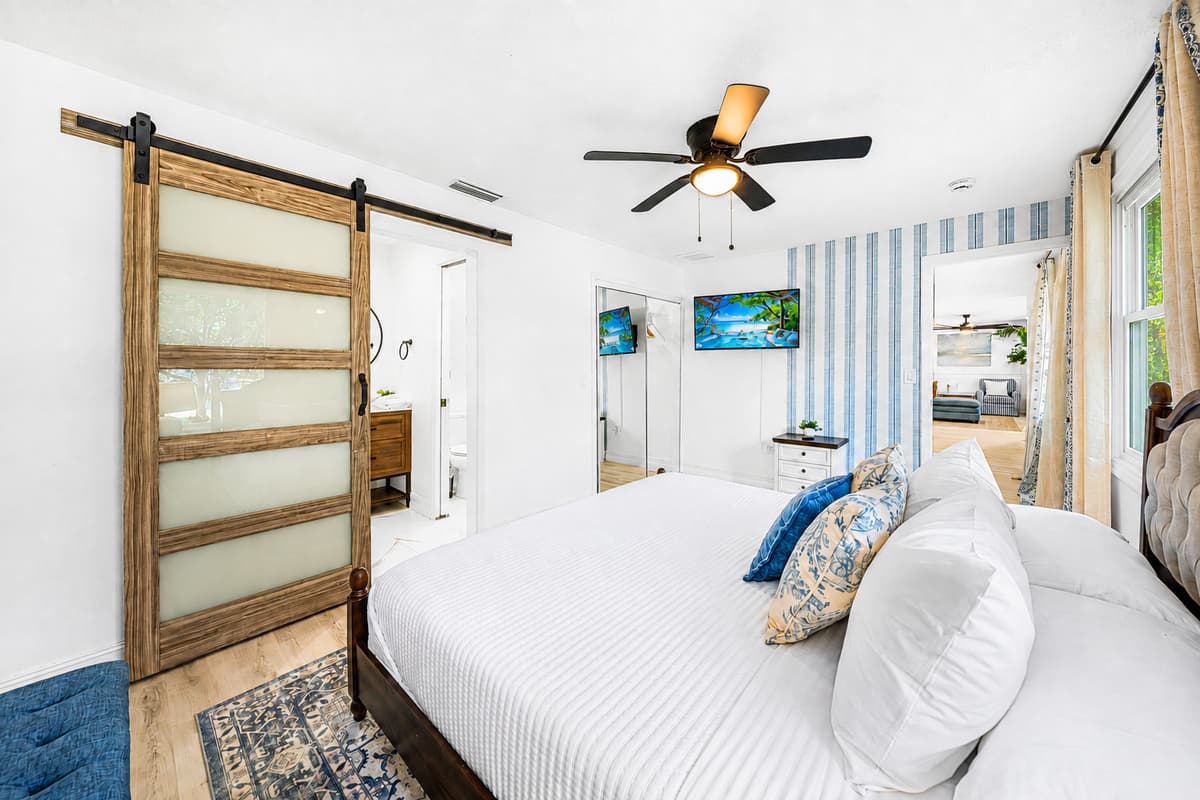 Four-poster bed, sliding barn door, TV on the wall — the room you'll retreat to when the house gets loud.
