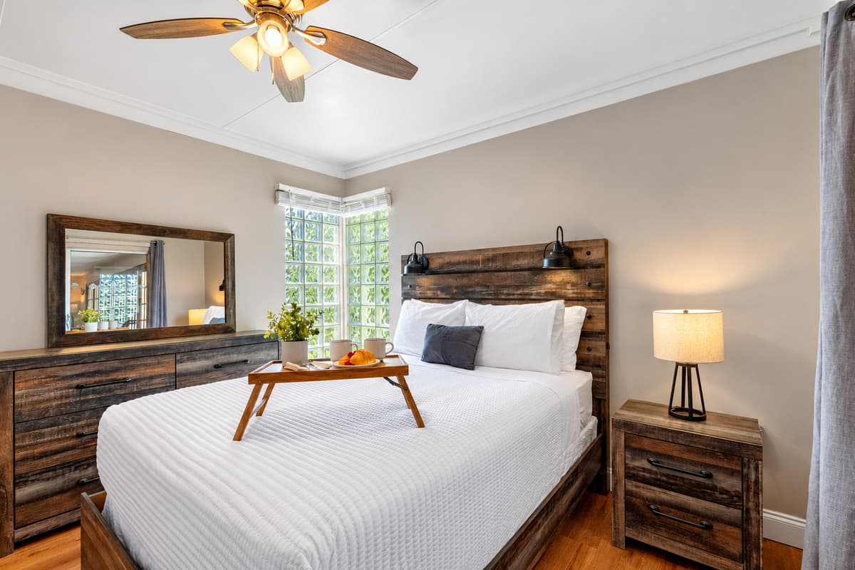 The natural wood furniture and headboard add a rustic charm, while modern touches create a balanced and stylish look.