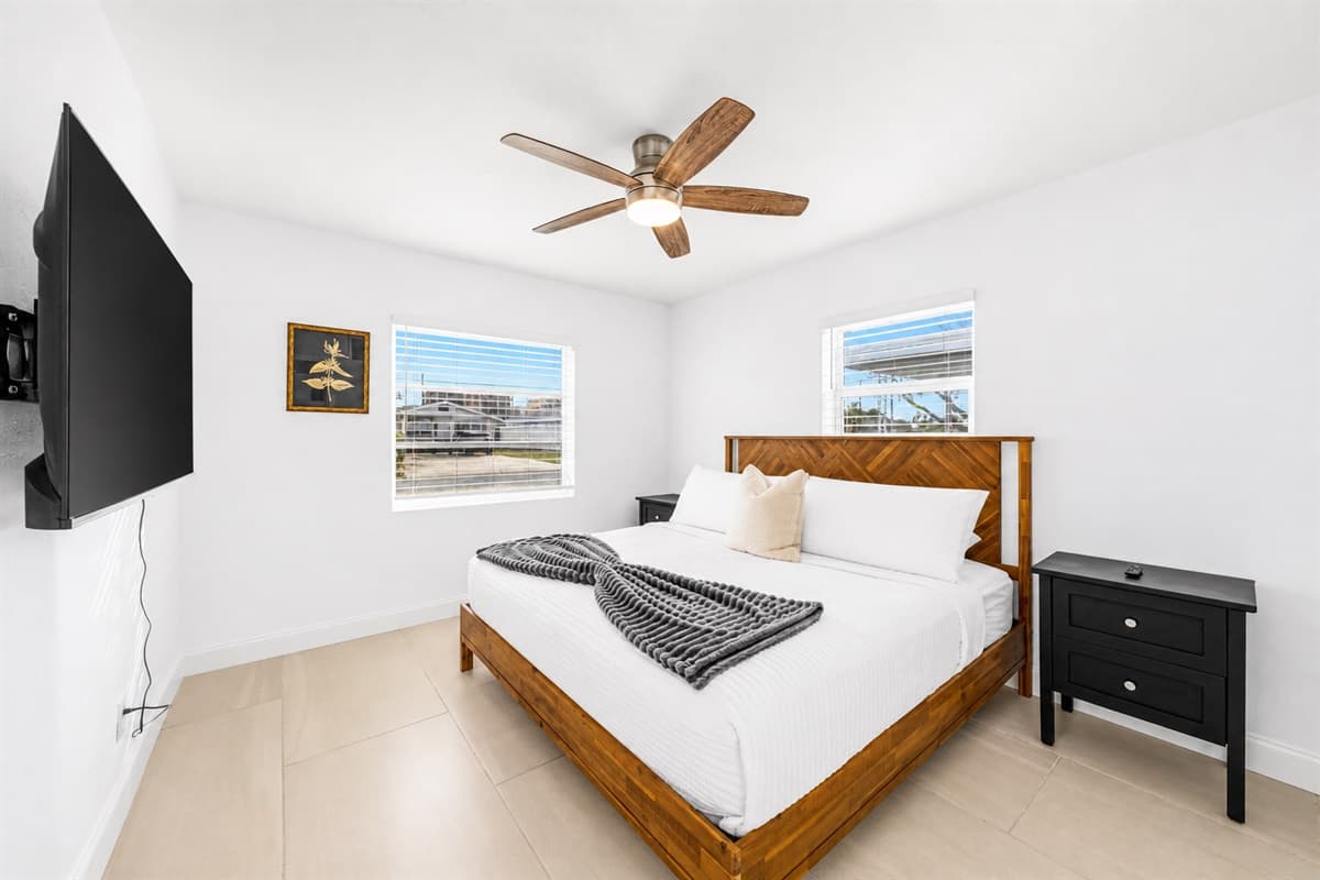 Spacious guest bedroom with comfortable bedding, ceiling fan, and smart TV entertainment.