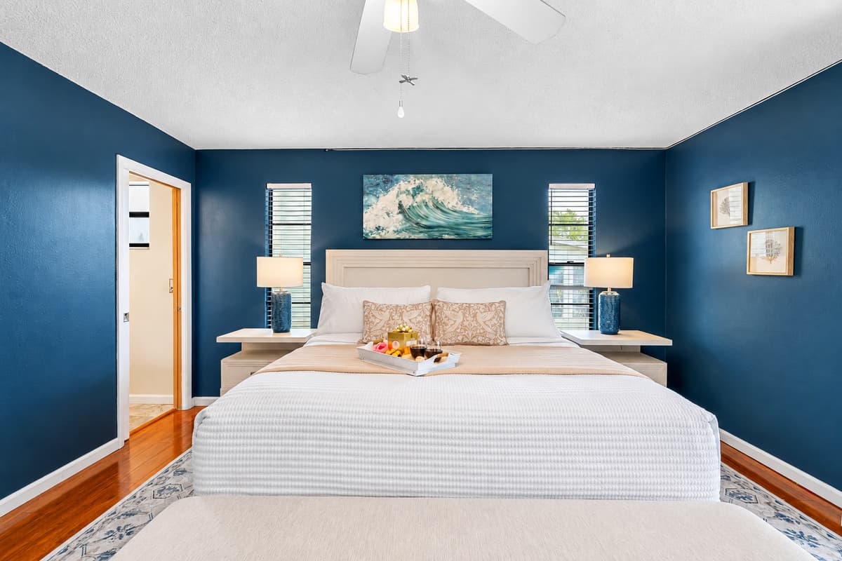 Featuring a luxurious king-size bed framed by a plush upholstered headboard and footboard with built-in storage, this room blends functionality and elegance effortlessly.