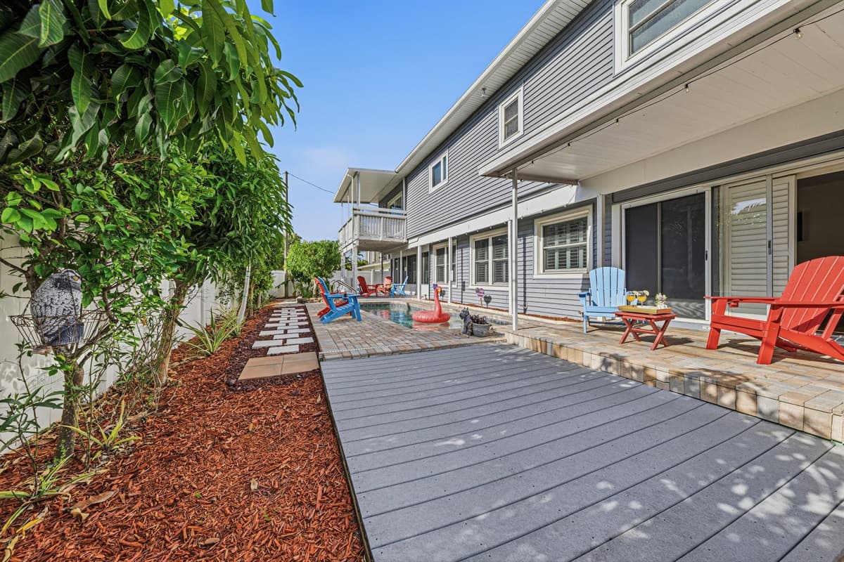 Wide backyard perspective with walkway leading to the pool and seating areas—inviting and well-designed outdoor space 
