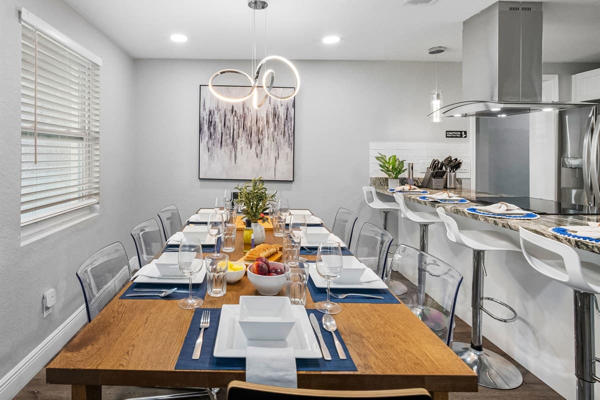 Sleek lines, minimalist décor, and a striking modern chandelier make this dining area a true centerpiece.