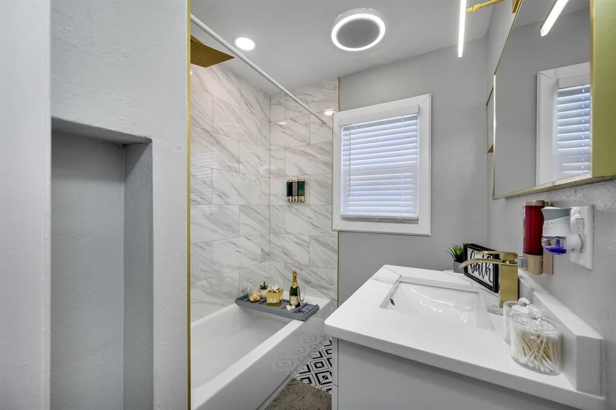 This bathroom has a bathtub, sink, toilet, shower, and wide vanity mirror.