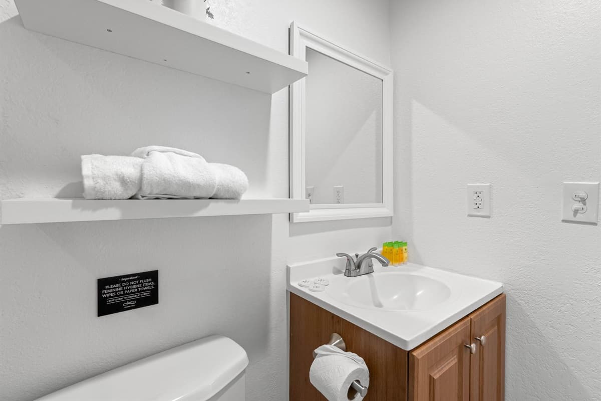Stylish primary en-suite bathroom offering a walk-in shower with elegant tile work, plush towels, and convenient open shelving.